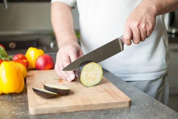 Profesyonel şef patlıcan üstünde a ahşap tahta bir seramik bıçak kullanarak hızlı bir şekilde keser. Yakın çekim.