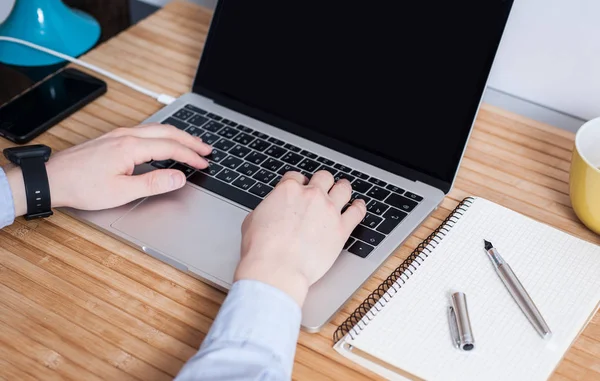 Bir adam vintage ahşap masa üzerinde bir dizüstü bilgisayar kullanarak çalışıyor. Tipik bir klavye üzerinde el. Mockup