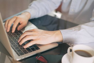 Genç bir adam onun laptop, adam ellerini meşgul ofis Masası, siyah masada oturan bilgisayarda yazarak genç erkek öğrenci, dizüstü bilgisayar kullanarak çalışma Resim kırpılmış. Genç işadamı ofiste dizüstü bilgisayar ile çalışma