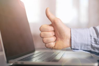 Adamın elini poz parmak başparmak yukarı (gibi) ile dizüstü bilgisayar