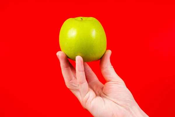 Mano sosteniendo sabroso verde orgánico deliciosa manzana Aislado en rojo — Foto de Stock