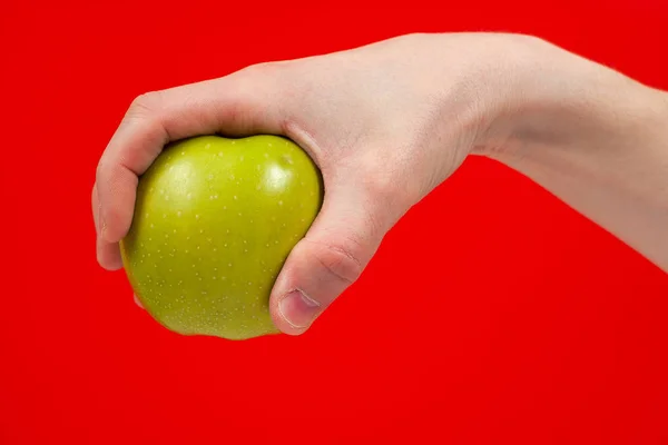 Mão segurando saborosa maçã verde orgânica deliciosa Isolado no vermelho — Fotografia de Stock