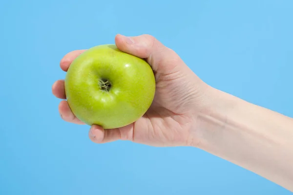 青い背景に隔離された有機おいしいリンゴを手に持つ — ストック写真