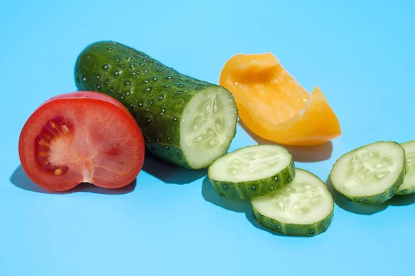 Rijpe groene komkommer, gele peper en rode tomaat op blauwe backgr — Stockfoto