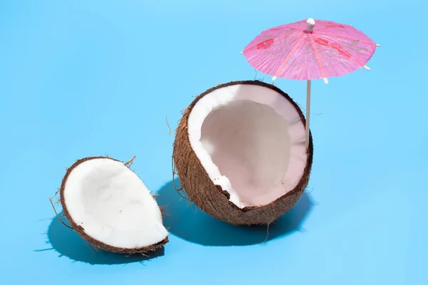 Coco fresco y jugoso con un paraguas de cóctel aislado en un azul — Foto de Stock