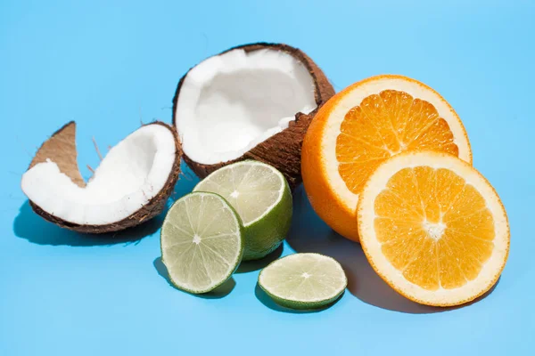 Świeży soczysty pomarańczowy, kokosowy i zielony wapno izolowane na niebieskim grzbiecie — Zdjęcie stockowe