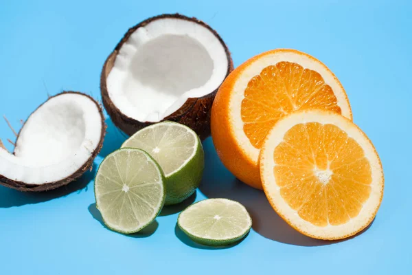 Świeży soczysty pomarańczowy, kokosowy i zielony wapno izolowane na niebieskim grzbiecie — Zdjęcie stockowe