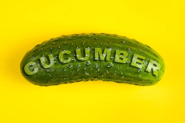 Fresh cucumber isolated on yellow background. Word CUCUMBER — Stock Photo, Image