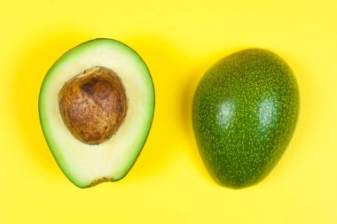 Doğal organik olgun avokado. Sarı arka planda yarım avokado.
