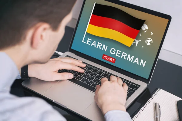 Man working on laptop with LEARN GERMAN on a screen. Education l