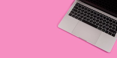 Dizüstü bilgisayarı, kalemi ve pastel pembe arka plan manzaralı güzellik masası düz yatıyordu.