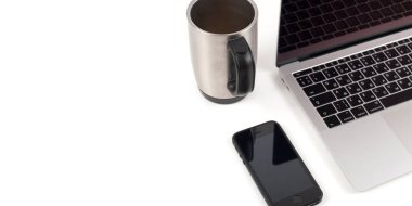Laptop ve cep telefonlu kahve fincanı beyaz arka planda izole edilmiş.