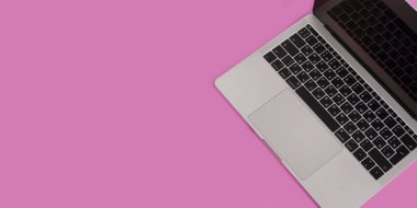 Dizüstü bilgisayarı, kalemi ve pastel pembe arka plan manzaralı güzellik masası düz yatıyordu.