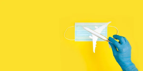 Eldivenle, model bir uçağı yüz maskesinin üstünde tutarak. Uçak yolculuğu seyahatten sonra devam eder. Açık kenarlar, karantina sonu.