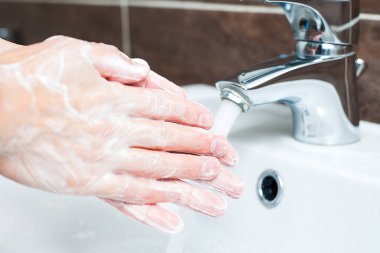 Hijyen konsepti. Musluğun altında sabunla ellerini yıkamak, suyla.