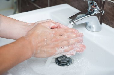 Hijyen konsepti. Musluğun altında sabunla ellerini yıkamak, suyla.