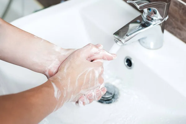 Hijyen konsepti. Musluğun altında sabunla ellerini yıkamak, suyla.
