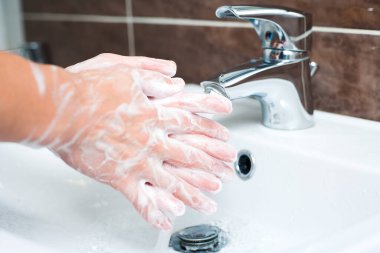 Hijyen konsepti. Musluğun altında sabunla ellerini yıkamak, suyla.