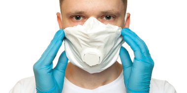 Lateks koruyucu eldivenli genç cerrah beyaz arka plana beyaz koruma maskesi takıyor. Tıbbi eldivenli ve koruyucu maskeli bir adam. Coronavirus COVID-19 koruması