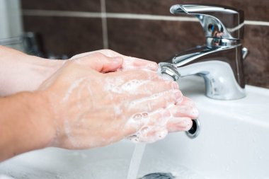 Hijyen konsepti. Musluğun altında sabunla ellerini yıkamak, suyla.
