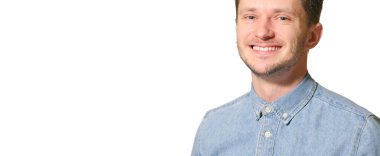 Genç yakışıklı adam mutlu ve şapşal görünüyor. Beyaz arka planda geniş, eğlenceli bir gülüşü var.