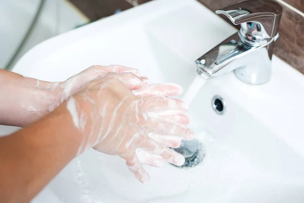 Hygiene concept. Washing hands with soap under the faucet with water