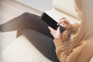 Ofiste boş ekranlı, elinde siyah cep telefonu olan bir kadının ellerinin görüntüsü.