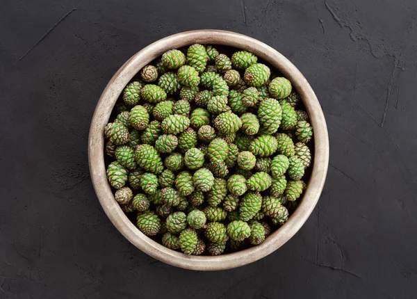 Green pine cones in a wooden bowl. Harvest young green cones for culinary and herbal medicine. Edible spring plant