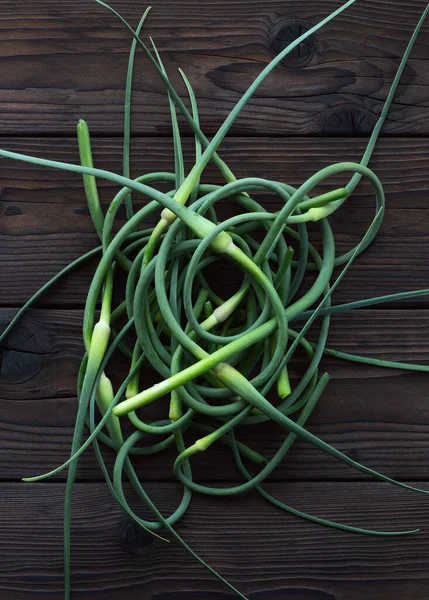 Knoblauchpfeile Auf Einem Dunklen Holztisch Ein Bund Frischer Knoblauchsprossen Knoblauch — Stockfoto