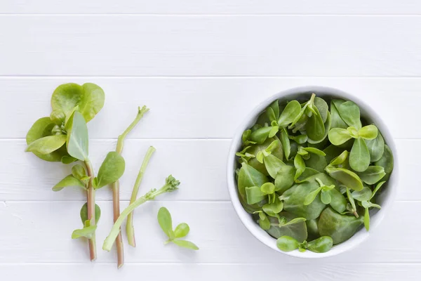 紫色の葉と白い木製のテーブルの上の小枝 庭から新鮮なPurslane 可食雑草 ハーブ ビーガン料理の成分 — ストック写真