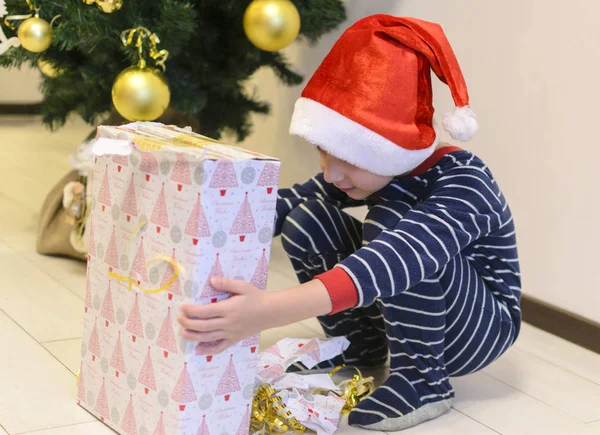 Chłopiec Santas Kapelusz Piżamy Znalezionych Trzyma Prezent Pod Choinkę Fotografia — Zdjęcie stockowe