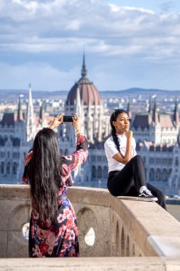 Budapeşte, Macaristan - 11 Şubat 2020: Instagram etkileyicileri, güneşli kış sabahlarında parlamentonun arka planında fotoğraf çekimi için poz verdiler