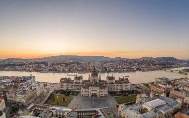 Macaristan Parlamentosu 'nun Budapeşte' nin Kossuth Meydanı 'ndaki Tuna nehri kıyısında kışın gün batımında hava aracı görüntüsü.