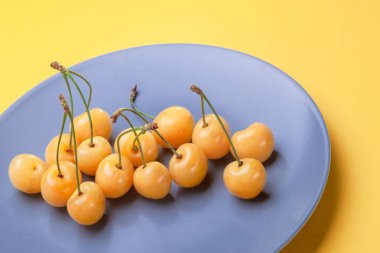 Çilek sarı sarı arka plan, doğal ürün, iyi bir fikir için stok üzerinde mavi plaka üzerinde kiraz.