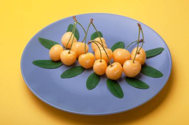 Çilek sarı sarı arka plan, doğal ürün, iyi bir fikir için stok üzerinde mavi plaka üzerinde kiraz.