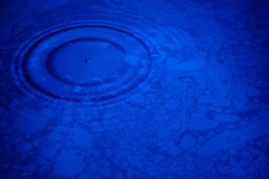 Closeup mavi dalga su ve yağ alan desen Yüzükler, havuzu daire yansımalar.