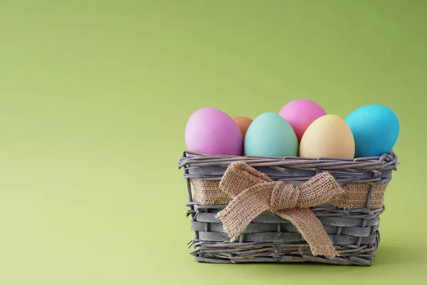 Frohe Ostern, gefärbte bunte Eier im Korb auf dem einfarbigen Hintergrund. — Stockfoto