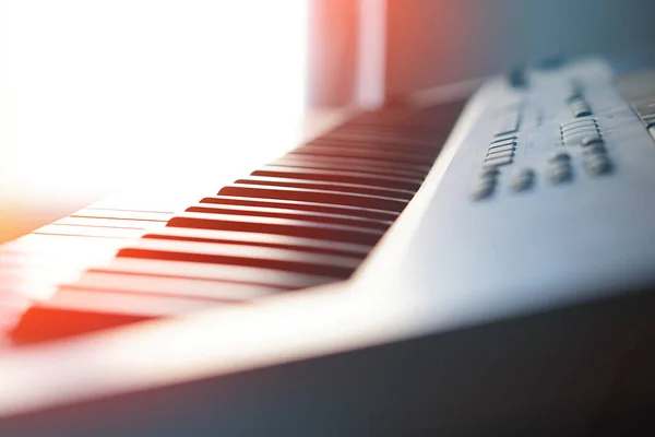 Tastiera per pianoforte sintetizzatore elettronico ai raggi del sole macro . — Foto Stock