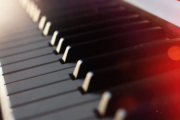 Tastiera per pianoforte sintetizzatore elettronico ai raggi del sole macro . — Foto Stock