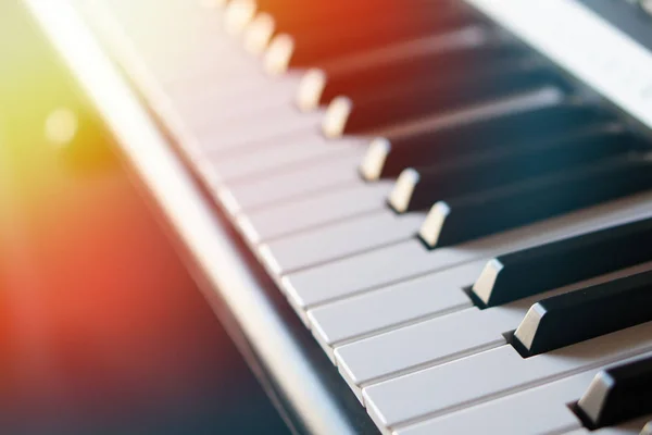 Tastiera per pianoforte sintetizzatore elettronico ai raggi del sole macro . — Foto Stock