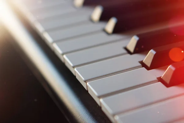 Tastiera per pianoforte sintetizzatore elettronico ai raggi del sole macro . — Foto Stock