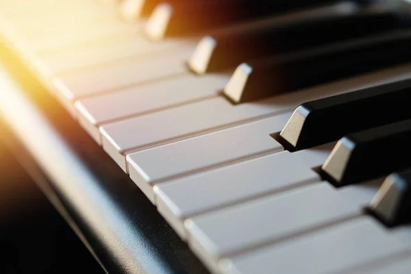 Tastiera per pianoforte sintetizzatore elettronico ai raggi del sole macro . — Foto Stock