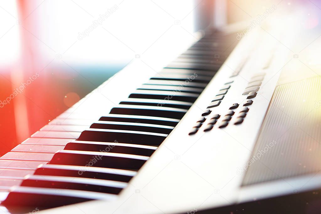 Electronic synthesizer piano keyboard in the sun's rays macro.