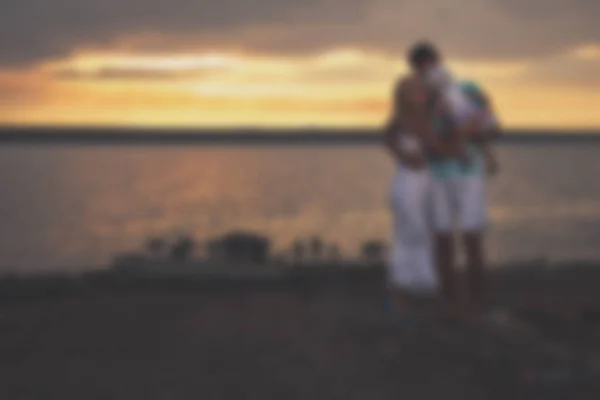 Sfocato - giovane famiglia lesbica omosessuale femminile al tramonto sul lago . — Foto Stock