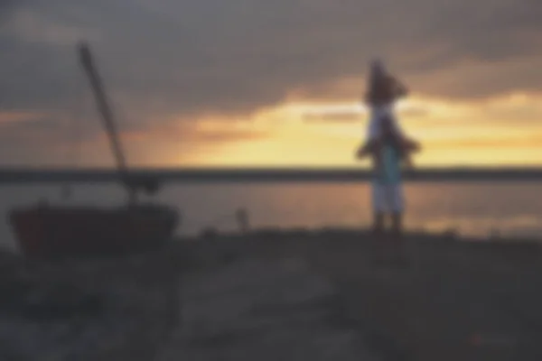 Blurred - young family father mother and daughter at sunset on the lake. — Stock Photo, Image