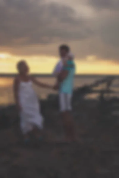 Sfocato - giovane padre di famiglia madre e figlia al tramonto sul lago . — Foto Stock