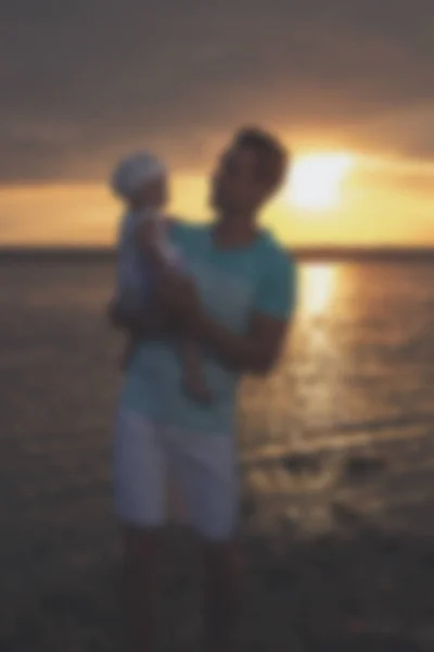 Verschwommen - junger Vater und seine Tochter bei Sonnenuntergang am See. — Stockfoto