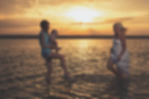 Wazig - jonge vrouwelijke homoseksuele lesbische gezin bij zonsondergang op het meer. — Stockfoto
