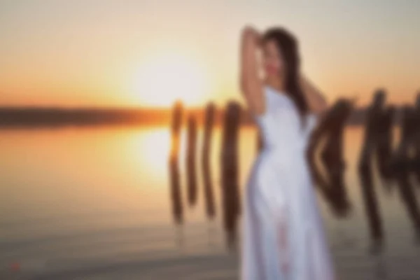 Wazige foto voor achtergrond, Angel bij zonsondergang aan zee, goed idee fantasie. — Stockfoto