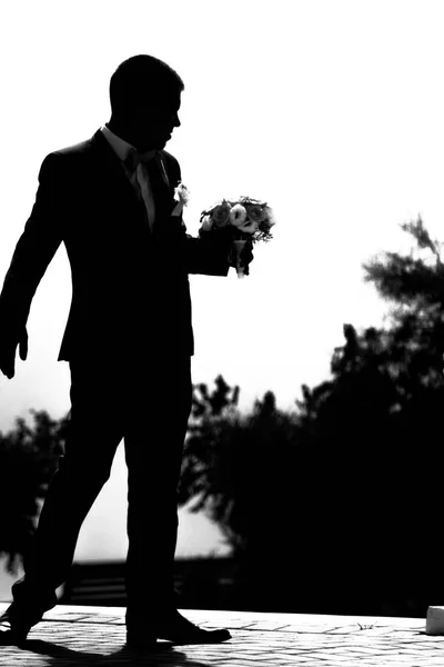 Groom silhouette with bow tie on shirt with a bouquet of flowers.